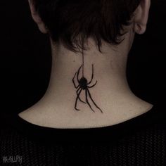 a woman's neck with a spider tattoo on the back of her upper body