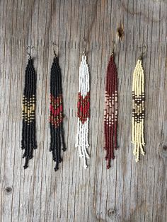 five seed beaded necklaces hanging on a wooden surface