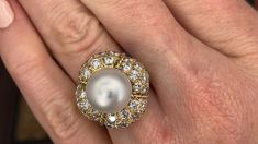 This magnificent cocktail ring is centered with one (1), post set, cultured South Sea pearl. The pearl tops a domed setting is bead set sixty-four (64), bead set, round brilliant cut diamonds. The ring has a split shank design and is accented with seven (7), bead set, round brilliant cut diamonds on each side. The ring measures 21.7mm at the top, rises 18.6mm above the finger, tapering to 2.4mm wide and 1.1mm thick at the base of the shank. The ring is currently size 7. Elegant White Domed Jewelry, White Pearl Ring With 17 Jewels For Formal Occasions, Elegant White Domed Rings, Luxury Domed Jewelry For Formal Occasions, Luxury Pearl Drop Ring For Formal Occasions, Luxury Pearl Ring For Evening, White Domed Jewelry For Anniversary, Luxury Evening Jewelry With Round Beads, Luxury Jewelry With Round Beads For Evening