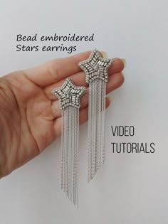 a hand holding two silver earrings with fringes on each side and the words bead embroideded stars earings written below