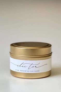 a gold tin with a white label that says,'i see natural soy candle '