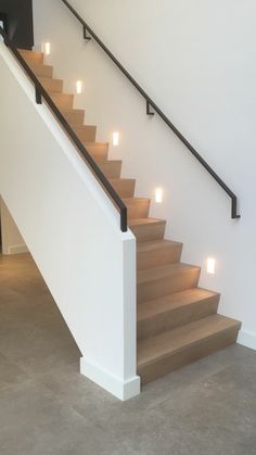 a set of stairs with lit candles on each handrail in an empty room next to a door