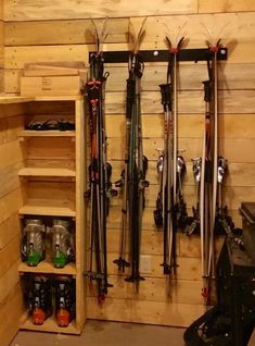 skis and snowboards are lined up against the wall in a storage area with wooden shelves