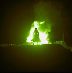 a woman standing in front of a green fire