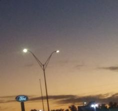 an empty parking lot at night with the lights on and street lamps in the distance