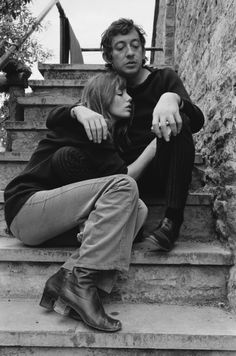 a man and woman sitting on some steps