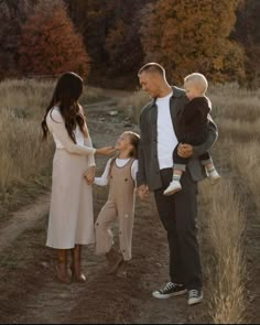 a family holding hands and walking down a dirt road