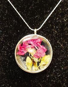 a glass pendant with flowers in it on a black surface