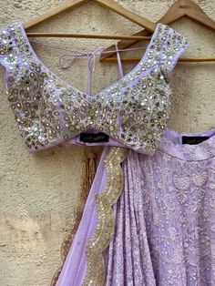 A three-piece lavender lucknowi mirror lehenga set from the Priti Sahni collection. This elegant lavender georgette lehenga with heavy gota, sequins, pearl and zari work border is paired with lavender blouse in raw silk fabric with mirror, pearl and zardozi hand work embroidery. The lehenga has side hanging ball tassels to the waistline. And the blouse has a sequins tassel tie-up at the back. The outfit is completed with a lavender mirror net dupatta with scalloped edging. Elegant Lavender Sharara With Zari Work, Designer Lavender Sets With Mirror Work, Lavender Sharara With Resham Embroidery For Diwali, Elegant Lavender Dupatta With Intricate Embroidery, Elegant Lavender Embroidered Dupatta, Designer Lavender Sharara With Zari Work, Designer Lavender Sharara For Diwali, Lavender Designer Sharara For Diwali, Lavender Bollywood Sharara For Designer Wear