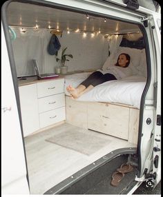 a man laying on top of a bed in the back of a white van with its doors open