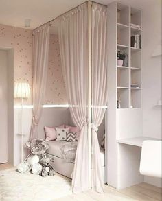 a white bedroom with pink curtains and teddy bear