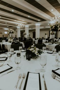 the tables are set with place settings and silverware for an elegant wedding reception in black and white