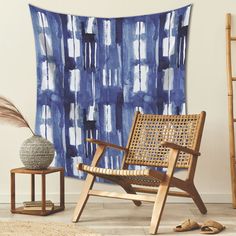 a wooden chair sitting in front of a blue and white wall hanging on a wall