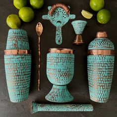 a set of teal and copper vases with matching utensils, lemons and limes in the background