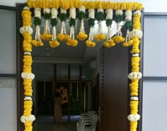 an entrance decorated with yellow flowers and white pom poms for the wedding ceremony