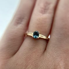 a woman's hand with a blue diamond ring on it