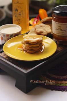 a yellow plate topped with pancakes next to a jar of honey and cup of coffee