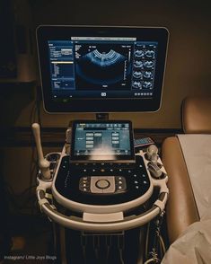 an electronic device is sitting in front of a monitor on a medical bed with leather chairs