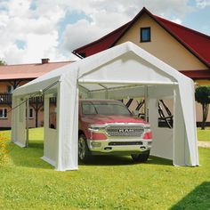 a red truck parked in front of a white tent on top of a green field