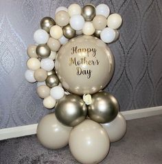 a mother's day balloon arch with white and gold balloons on it in front of a wall