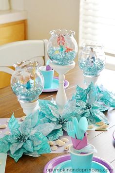 the table is set with plates, cups and vases filled with blue flowers on it