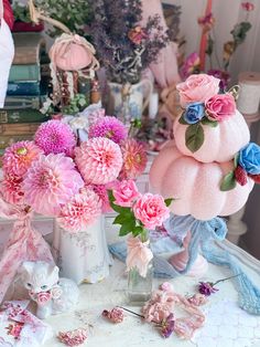 pink and blue flowers in vases sitting on a table next to other decorative items