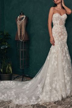 a woman in a wedding dress standing next to a mannequin on the floor