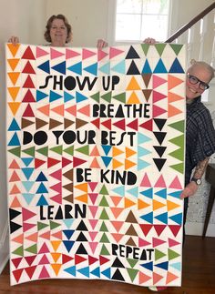 two people holding up a colorful quilt with words on it that read show up breathe your best be kind learn repeat