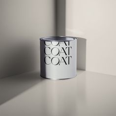 a white paint can sitting on top of a table next to a wall with the words coat coat written on it