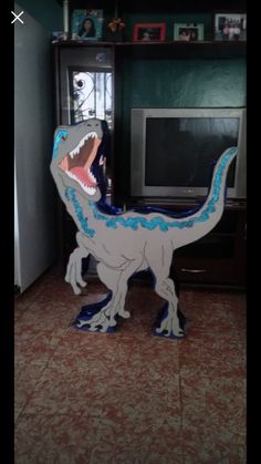 an inflatable t - rex standing next to a tv and bookcase with pictures on it