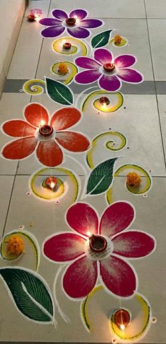 colorful flowers and leaves are on the floor with candles in front of them, which is decorated