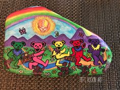 there is a painted rock with bears and rainbow colors on it, sitting on the ground