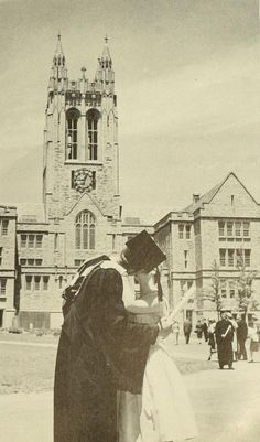 an old black and white photo of two people in front of a building with a clock tower