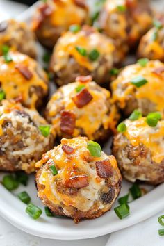 a white plate topped with mini meatballs covered in cheese and green onion garnish