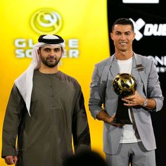 two men standing next to each other holding soccer balls in front of a yellow background