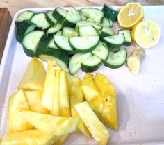 sliced cucumbers and lemons on a cutting board next to some cut up fruit