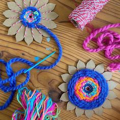 several different colored yarns and flowers on a wooden table with scissors, thread and twine