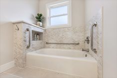 a bathroom with a bathtub, window and towel rack on the wall next to it