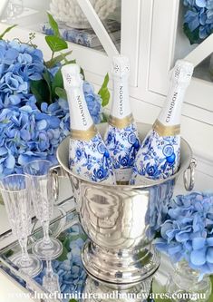 blue hydrangeas and champagne bottles in a silver ice bucket on a mirrored tray