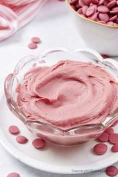 a bowl filled with pink colored food on top of a white plate next to a bowl full of red candies