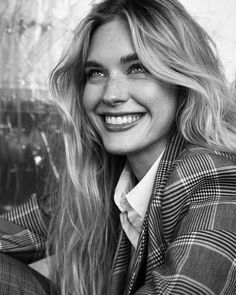 black and white photograph of a woman with long blonde hair wearing a jacket smiling at the camera