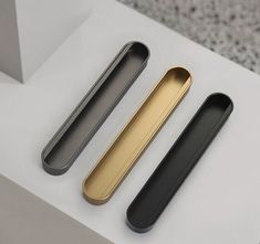 three black and gold items sitting on top of a white table next to each other