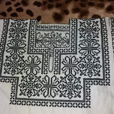 a white and black table cloth with cross designs on it sitting on a leopard print rug