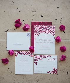 the wedding stationery is laid out on the floor with rose petals scattered around it