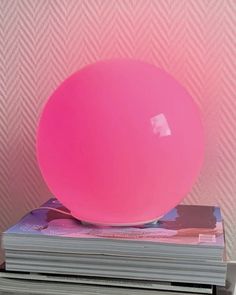 a pink ball sitting on top of stacks of magazines