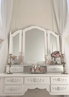 a white dresser with two mirrors on top of it