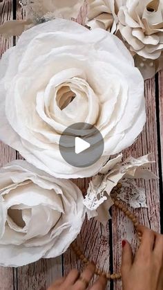 paper flowers are being made with scissors and string on a wooden surface, while someone is working