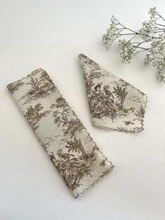 two pieces of fabric sitting on top of a table next to a vase with flowers