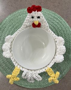 a crocheted chicken sitting on top of a white bowl with yellow chicks around it