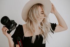 a woman in a white hat holding a camera